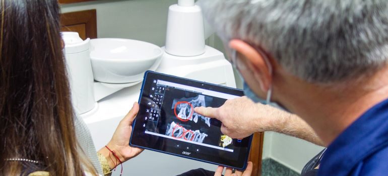 Orthodontist points toward X-ray of patients teeth.